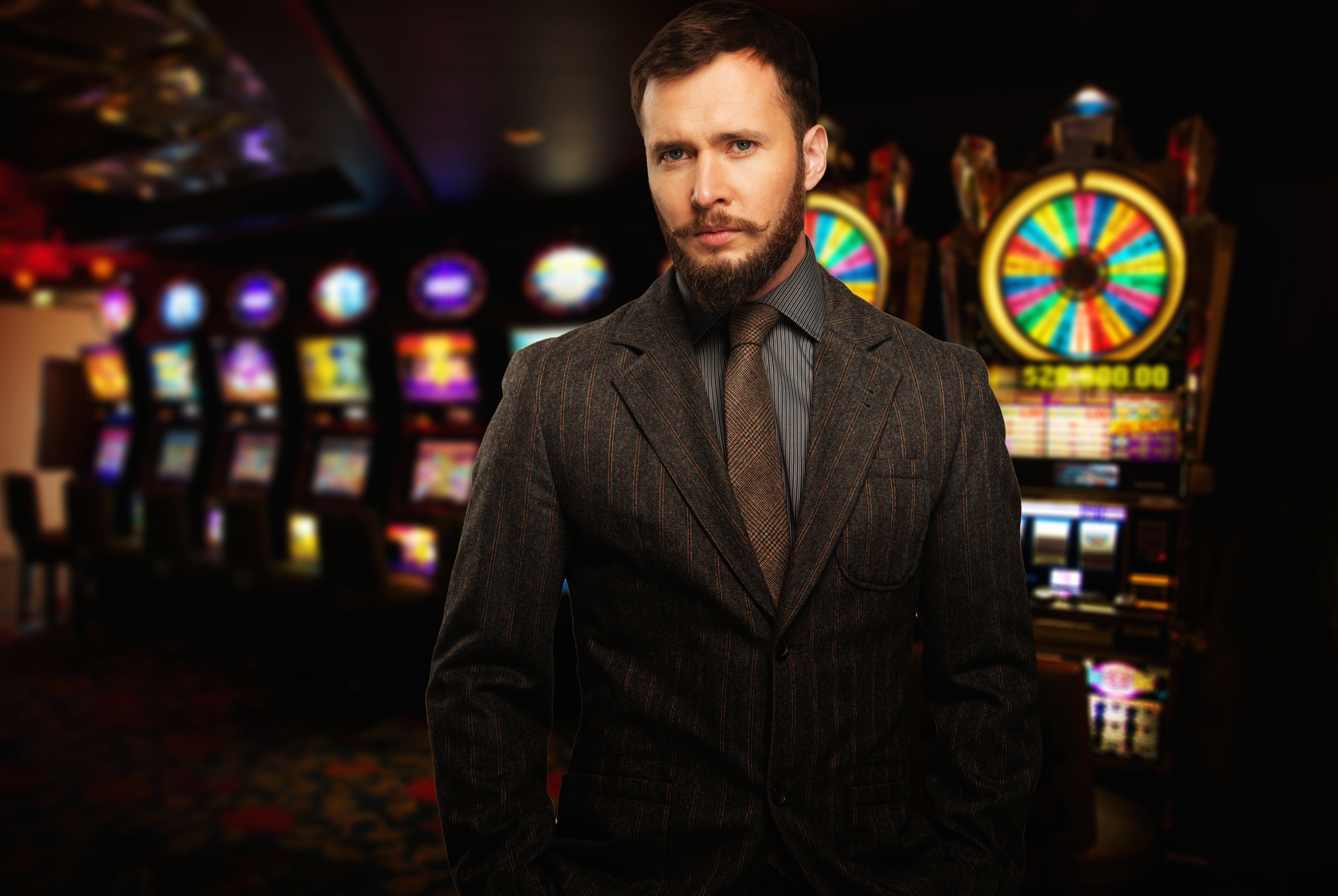 Handsome well dressed man against slot machines in a casino